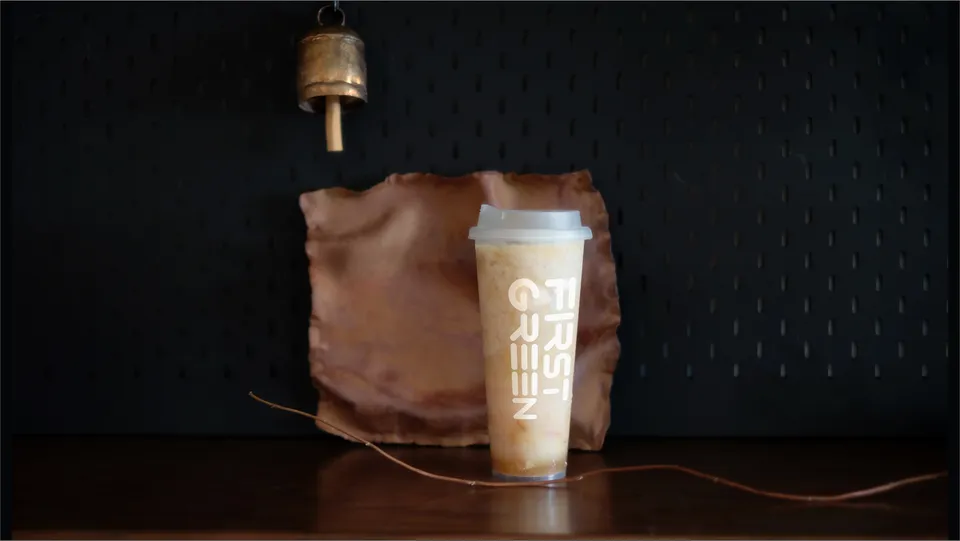 A FirstGreen matcha milk drink in a branded cup